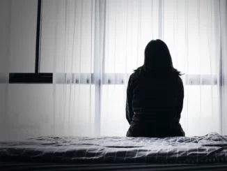 Kvinna sitter i en säng, deprimerad