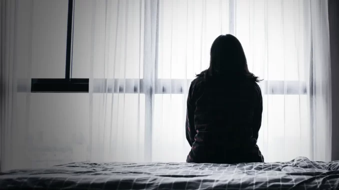 Kvinna sitter i en säng, deprimerad