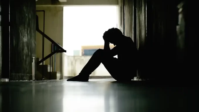 Person sitter i en mörk trappuppgång, deprimerad