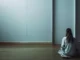 Kvinna sitter i ett rum tittar på en dörr utan dörrhandtag